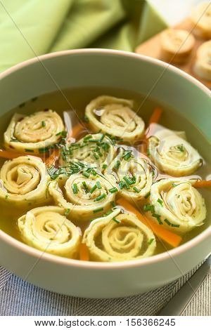 Traditional German Flaedlesuppe and Austrian Frittatensuppe based on consomme with rolls or stripes of pancake or crepe garnished with chives photographed with natural light (Selective Focus Focus one third into the image)