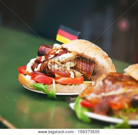 Street food german burger with sausage vegetables ketchup and mayonnaise. Street food or unhealthy food concept.