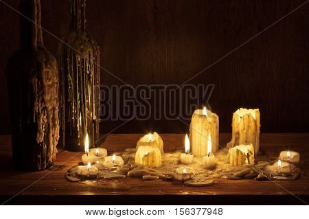 Melting Candle In Wooden Shelf With Bottle