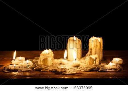 Melting candle in wooden shelf on black background