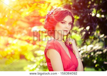 Beautiful girl on the nature in the park. Against the background of the summer lanshaft. Young romantic woman in the sunshine, sunset.