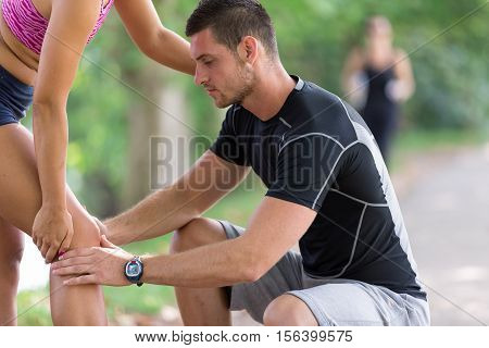 Man helps to woman with injured knee at sport activity.