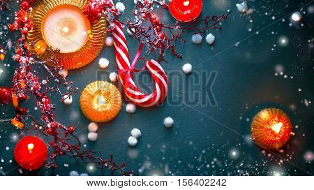 Christmas Holiday Background with Candy Cane, decorations, candles, garland and evergreens border over dark background table. Christmas and New year food. Christmas dinner, served table, decorations