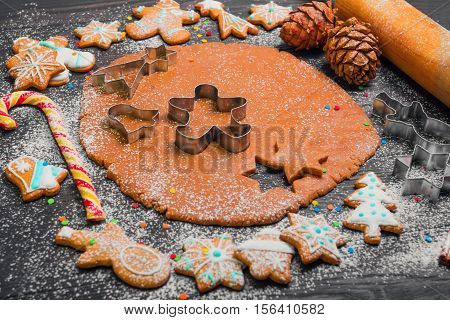 Cooking Christmas cookies gingerbread. On a dark brown background gingerbread dough. Forms for Christmas cookies gingerbread rolling pin cones. Cookies with icing. Christmas New Year card.