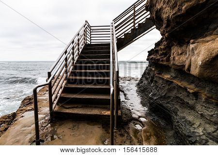 Sunset Cliffs in San Diego, California ocean access staircase for surfers on a stormy day.