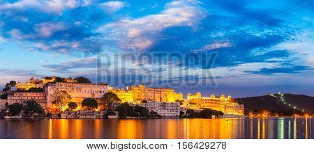 Panorama of famous romantic luxury Rajasthan indian tourist landmark - Udaipur City Palace in the evening twilight with dramatic sky - panoramic view. Udaipur, India