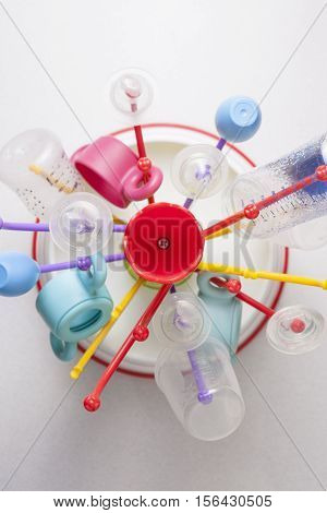 Baby drainer full of plastic tableware objects as baby bottles. High view angle