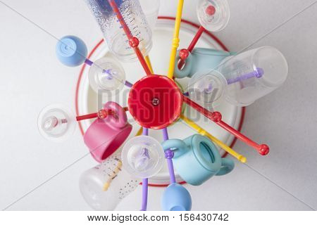 Baby drainer full of plastic tableware objects as baby bottles. High view angle