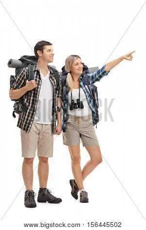Full length portrait of a female hiker showing something in the distance to a male hiker isolated on white background