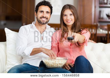     Young couple watching tv and eating pop-corn