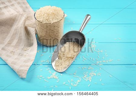 Metallic scoop with rice on wooden background