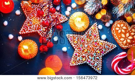 Christmas Holiday Background with ornate Gingerbread cookies, Candy Cane and evergreens border over black background table. Christmas and New year food. Christmas decoration