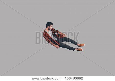 In mid-air. Mid-air shot of handsome young man jumping and gesturing against background