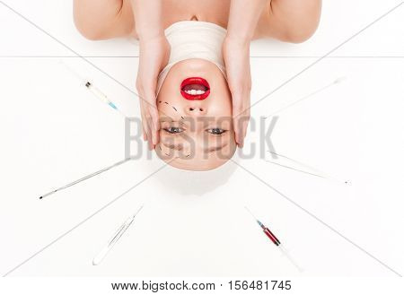 Unhappy woman in bandages. from above. with surgical instruments. head over heels