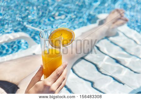 Woman enjoying a orange juice at the swimming pool