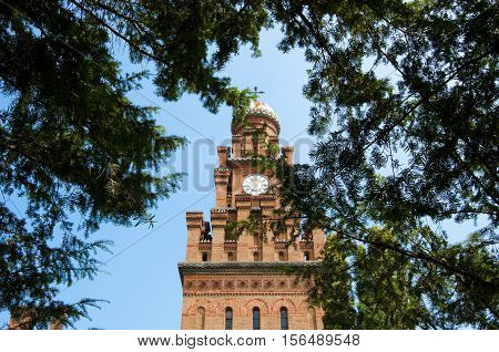 beautiful historical building of Chernivtsi national university religious seminary of red brick facade with green trees and bushes sunny outdoor in Ukraine