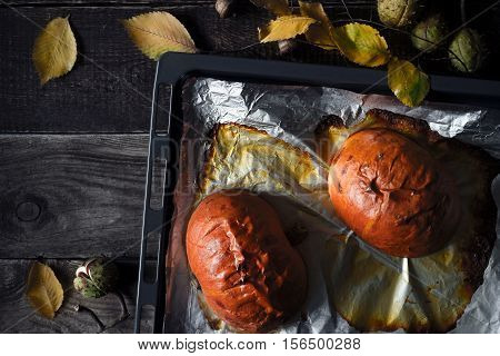 Halves of baked pumpkin on the baking tray on the wooden table top view