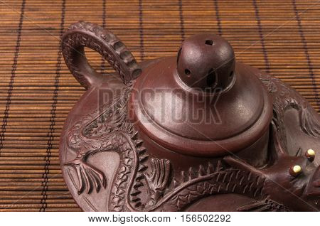 brown Chinese teapot of Yixing clay with traditional ornament on bamboo Mat