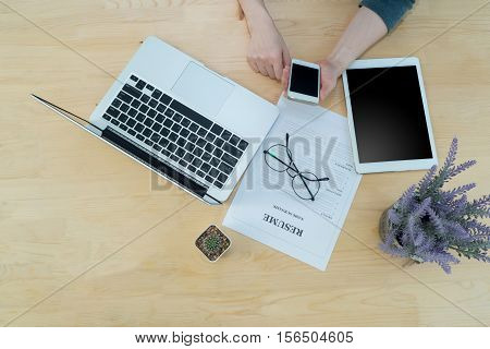 woman hold and touch blank screen on cell phone smartphone with Resume information modern glasseslaptop tablet and Cactus flower on pot. Concept of jop search.