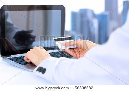 Business woman entering data of a credit card . On-line shopping on the internet using a laptop