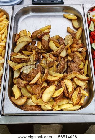 Steel container with roasted potato wedges, village style potatoes