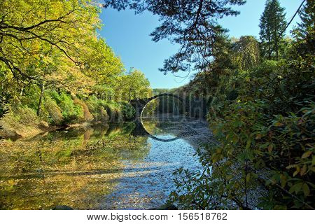 Arch Bridge in Kromlau, Saxony, Germany. Autumn in Park. Rakotz bridge in Kromlau