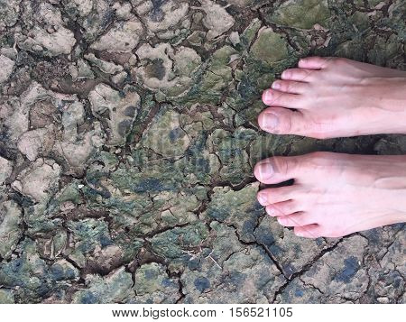 A barefoot standing on a cracked land.