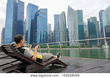 Man communicating via tablet with scyscrapers background in Singapore