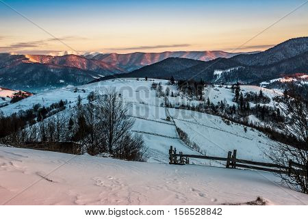 Fence On Snowy Mountain Slope Near The Forest In Winter
