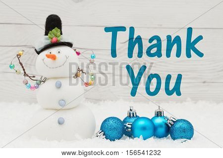 Thank you message Some snow Christmas ornaments and a snowman on weathered wood with text Thank You