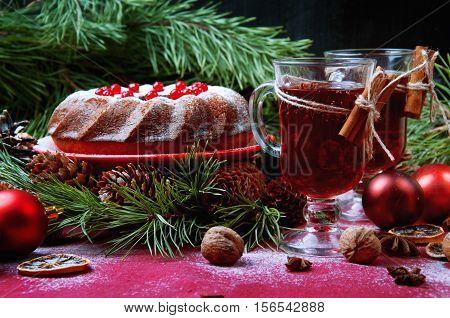 Christmas table setting. Bundt cake pudding sprinkled with sugar powder decorated with red currant and mulled wine.