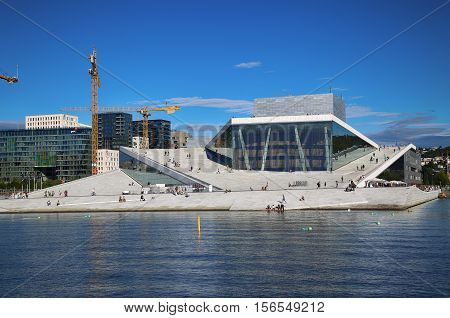 OSLO NORWAY - AUGUST 17 2016: Tourist on the Oslo Opera House which is home of Norwegian National Opera and Ballet and National Opera Theatre in Oslo Norway on August 172016.