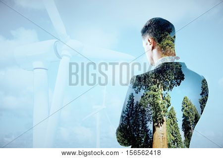 Thoughtful businessperson on sky background with wind mills. Double exposure. Eco friendly business concept