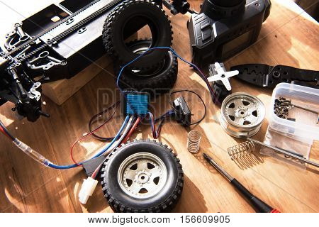 Building model cars. Radio control car assembly scene, RC car assembly on wooden work desk and tools. Natural lighting.