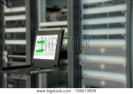 Monitor of monitoring system in data center room with blurred server in rack cabinet