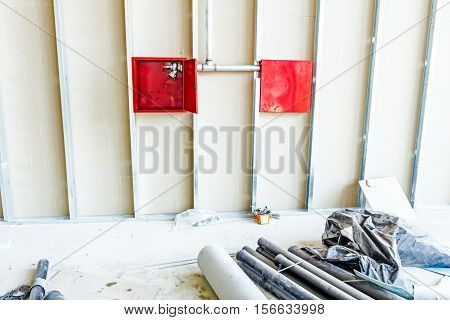 Red fire hydrant cabinet with extinguish valve is placed in an unfinished dry wall.