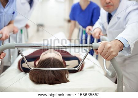 profession, people, healthcare, reanimation and medicine concept - group of medics or doctors carrying unconscious woman patient on hospital gurney to emergency room