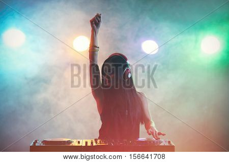 Pretty young DJ playing music in nightclub