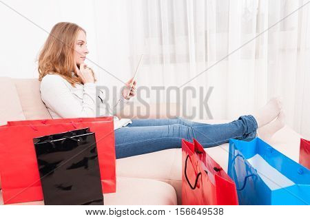 Lady Laying On Chouch Holding Tablet Being Pensive