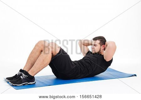 Fitness man shakes press in studion. on mat. isolated white background