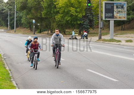 DNEPR UKRAINE - SEPTEMBER 25 2016:Active young father with son and daughter having bicycle ride on a Dnepr river embankment at weekend in Dnepr city, Ukraine at September 25,2016