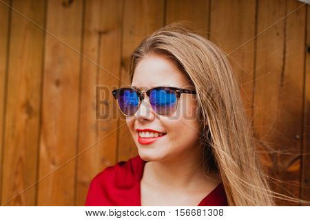 Happy blonde girl with red clothes and lips on a wooden background