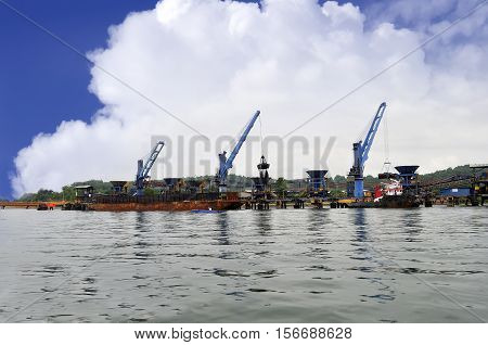 three crane unloading coal from barge to hopper