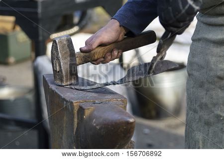 blacksmith forges detail. Blacksmith working outdoors. Master works on the anvil. Blacksmith makes a knife.