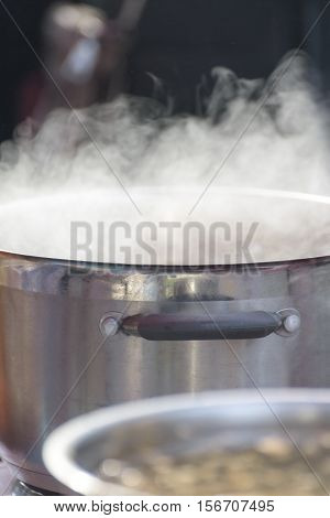 Steel pan with steam in the kitchen. Closeup