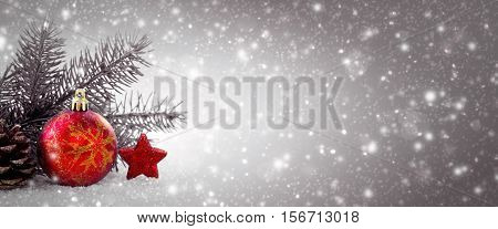 Christmas background with red bauble , star and green fir tree bransh .Christmas decoration and snowfall.
