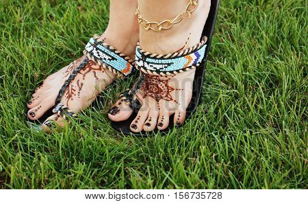Female legs with henna tattoo on green grass background