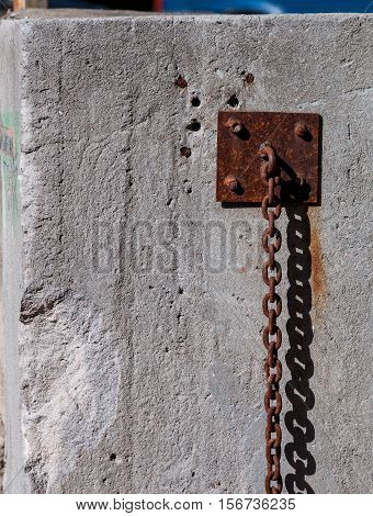 Old rusty chain mount on a concrete wall