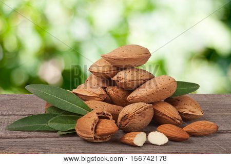 heap of almonds in their skins and peeled with leaf isolated on white background.