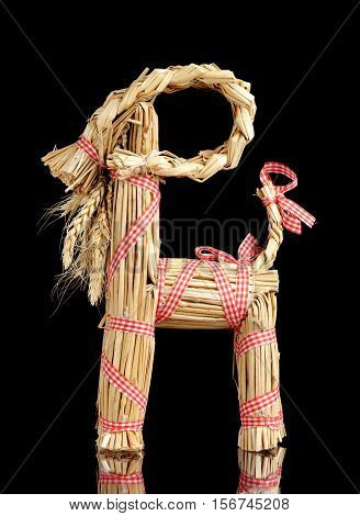 A traditional Swedish Christmas goat (julbock) made of straw on black background.